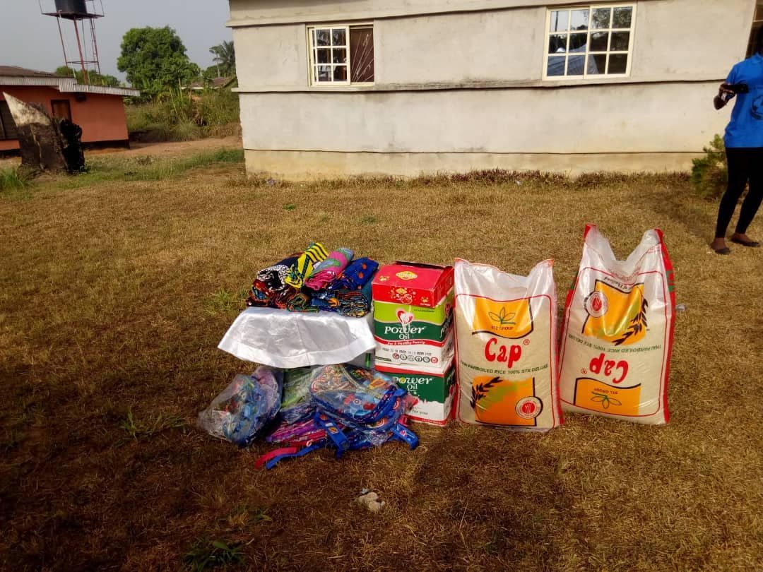 Three bags of rice are sitting on the ground in front of a house.