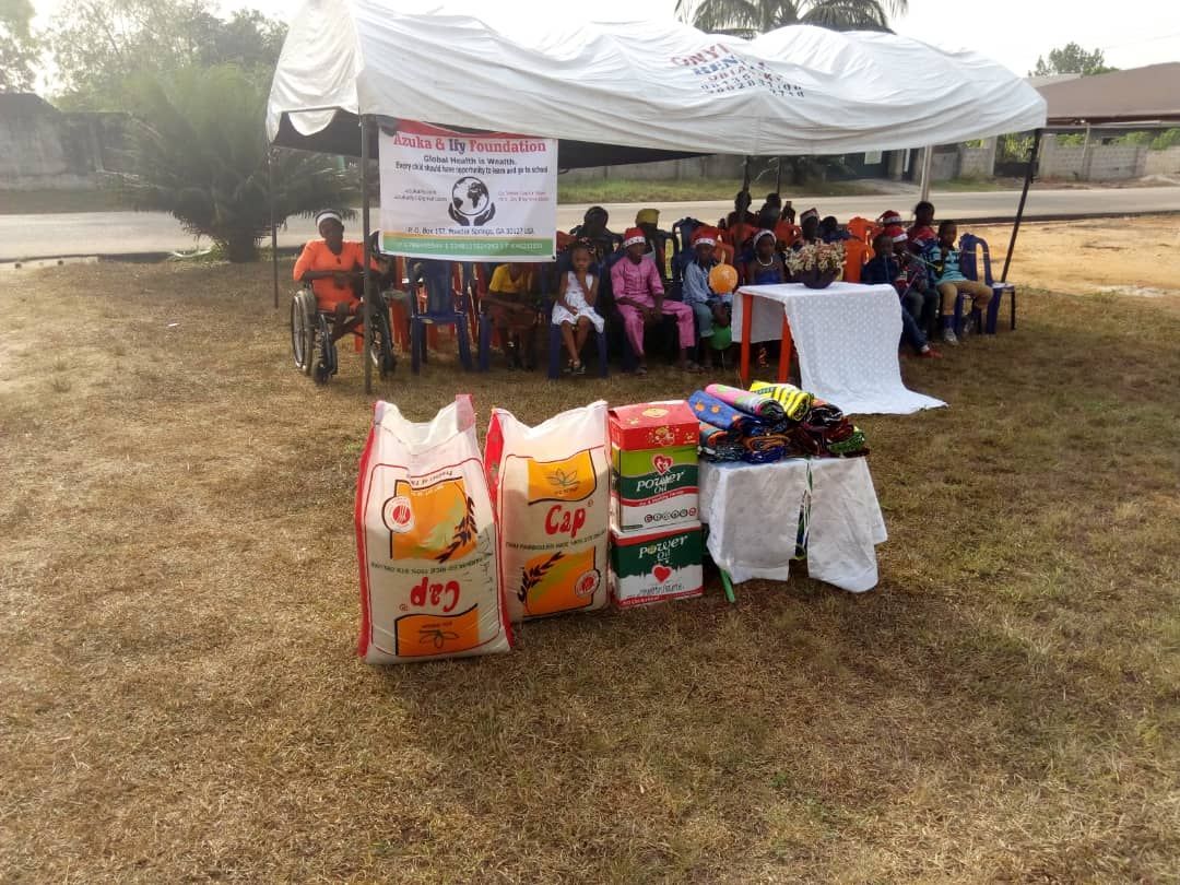 A group of people are sitting under a tent in a field.