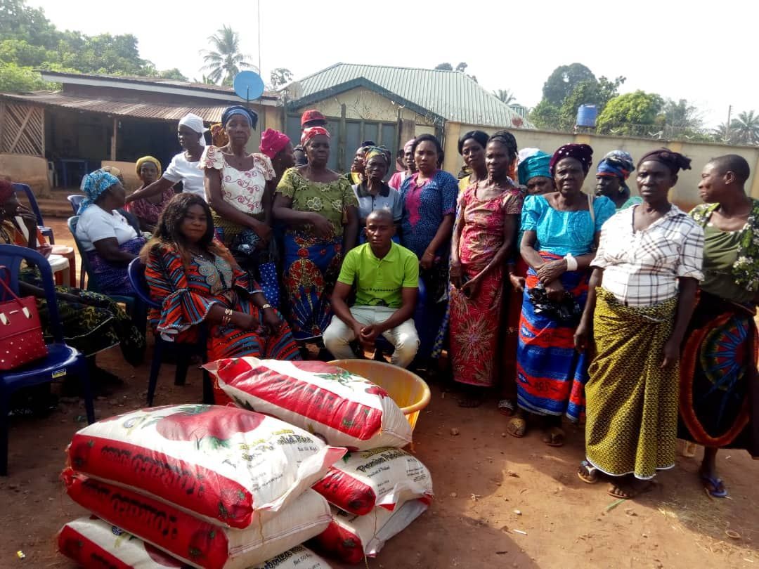 A group of people are standing around a pile of bags of rice.