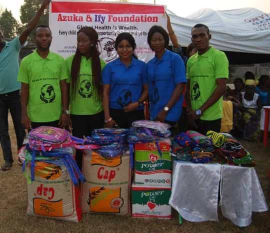 A group of people standing in front of a sign that says azuka & illy foundation