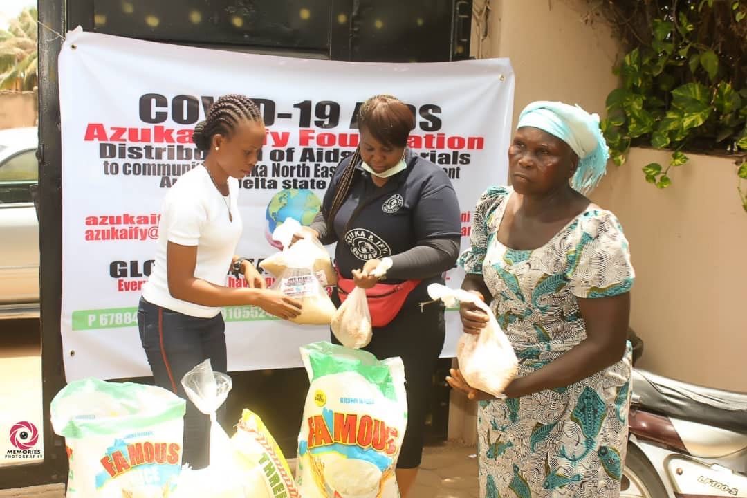 Three women are standing in front of a sign that says covid-19