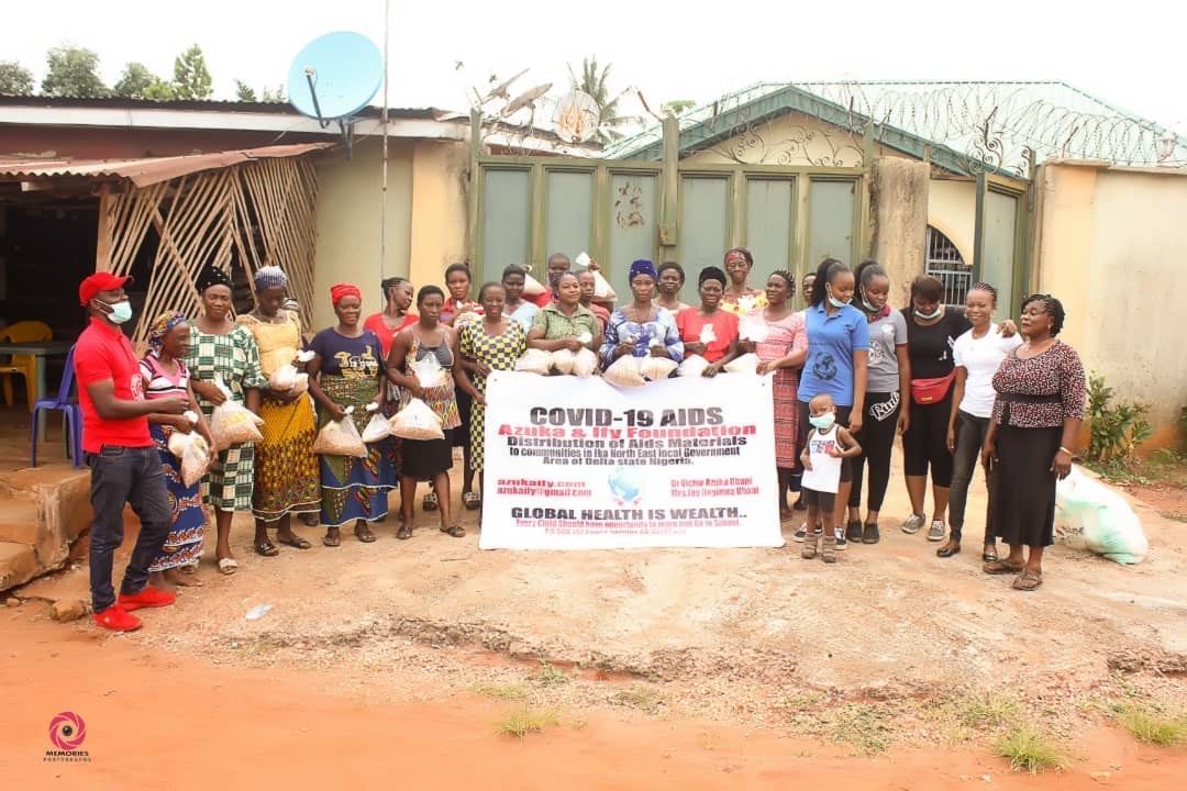 A group of people are standing in front of a house holding a sign.