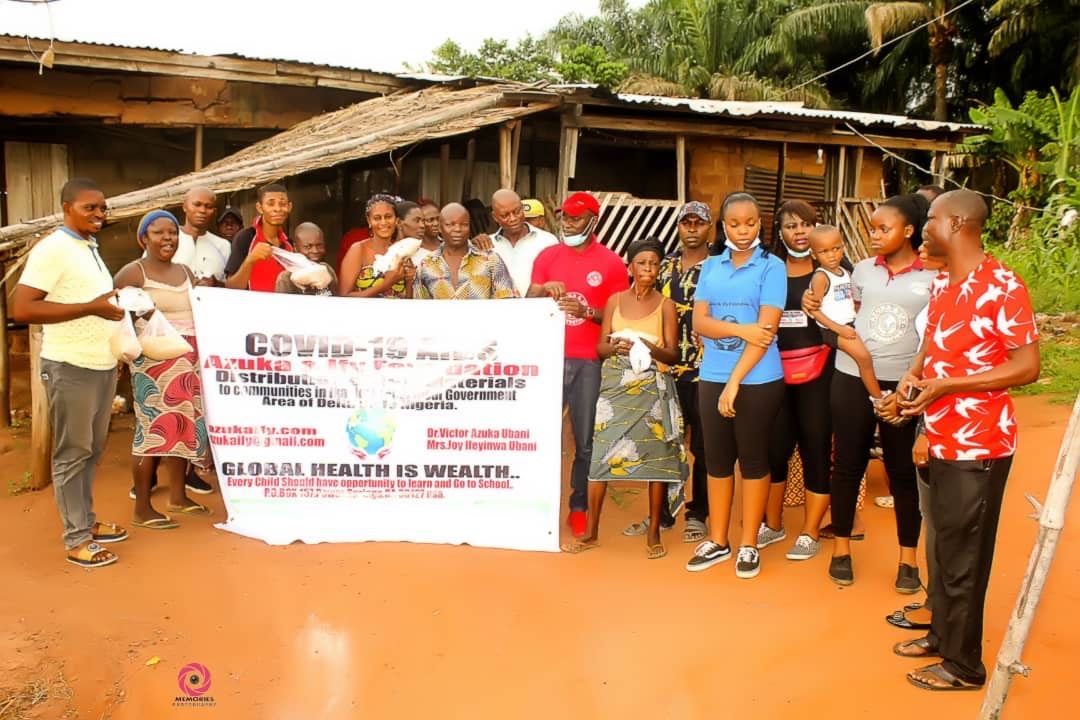 A group of people are standing in front of a house holding a sign.