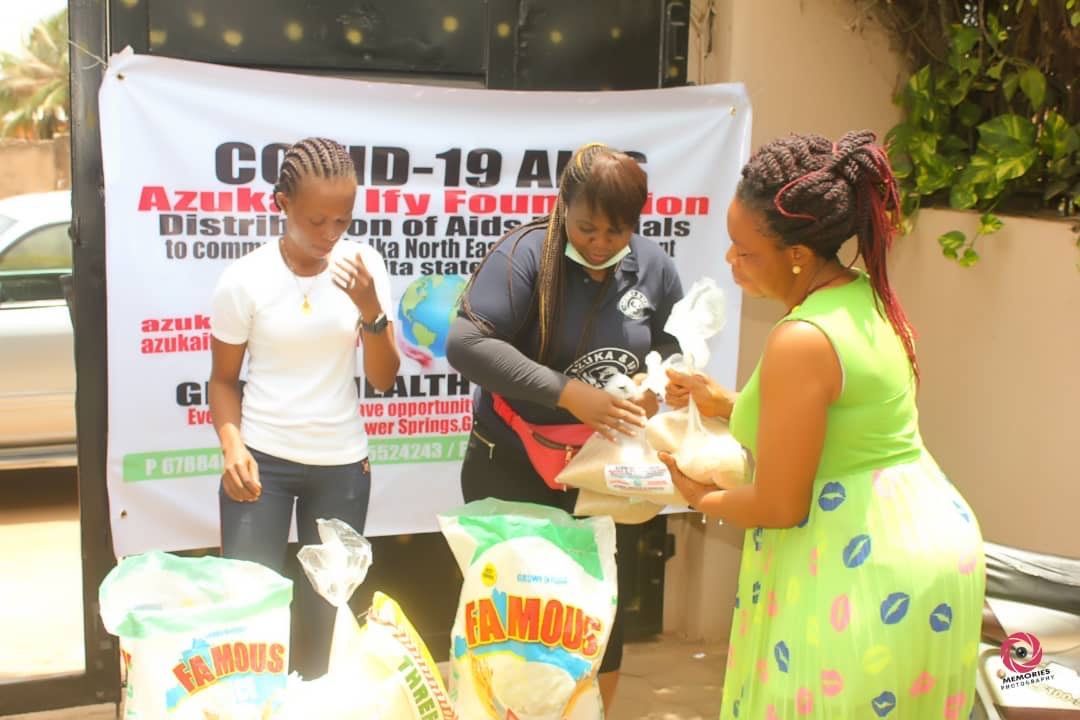 A woman in a green dress is giving a bag of food to another woman.