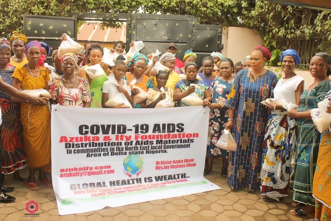 A group of women are standing in front of a sign that says covid-19 aids.