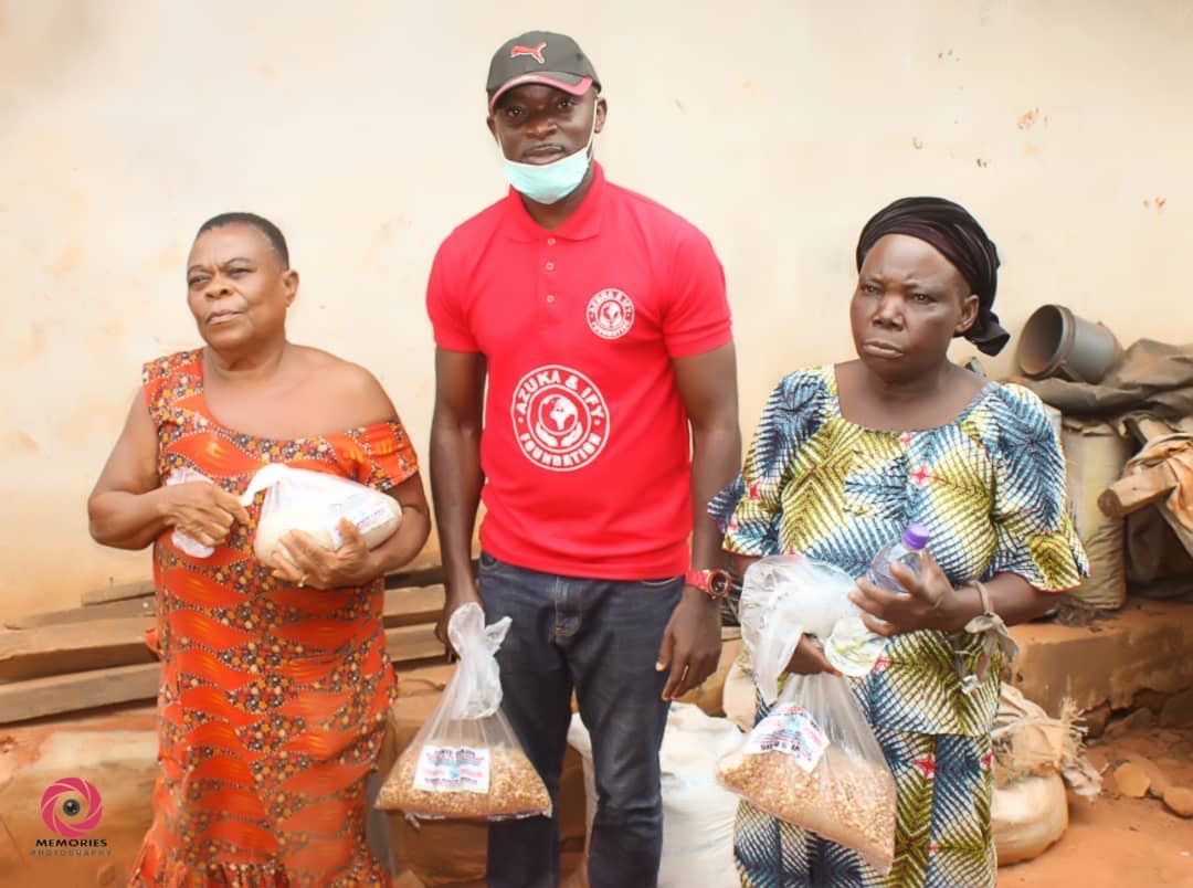 A man and two women are standing next to each other holding bags of food.