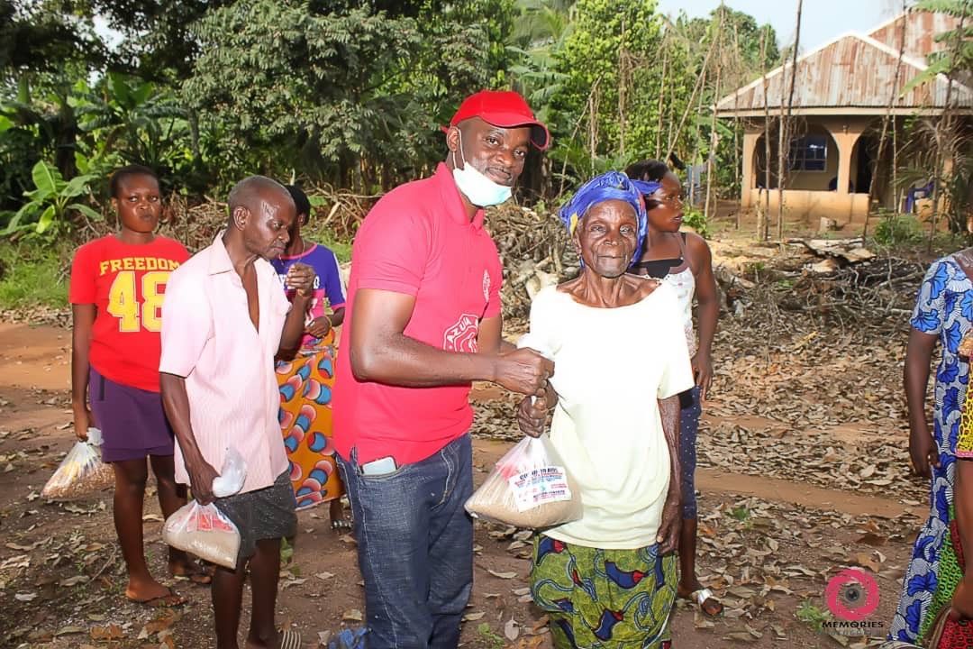 A man in a red shirt is giving a woman a bag of food.