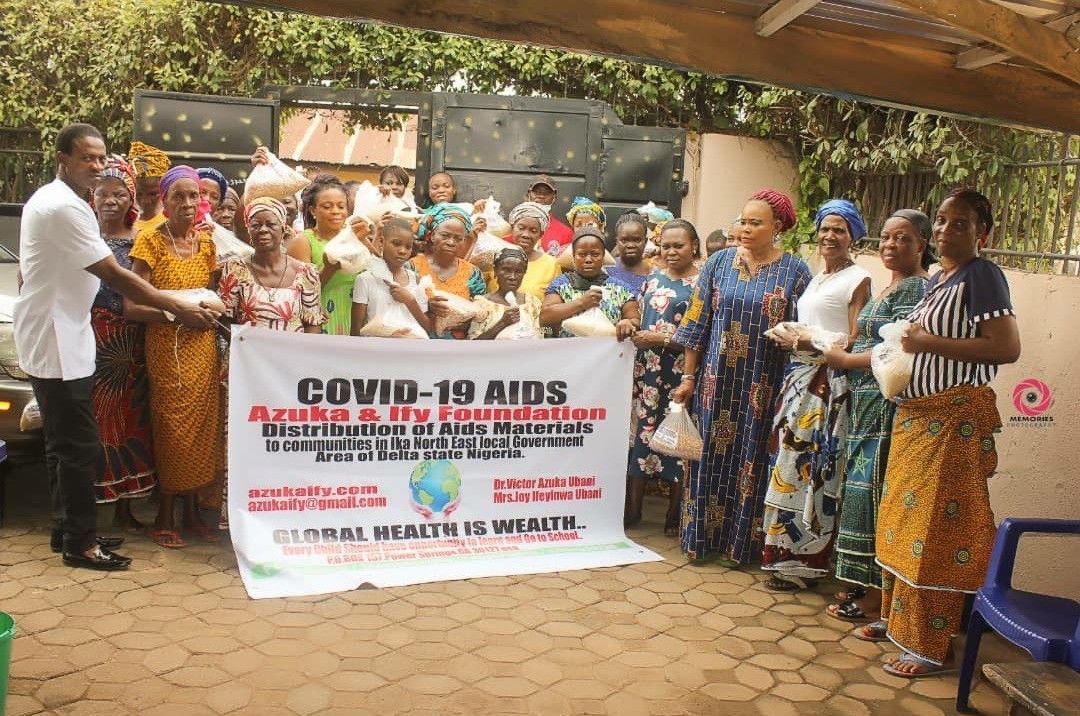 A group of people standing around a sign that says covid-19 aids.