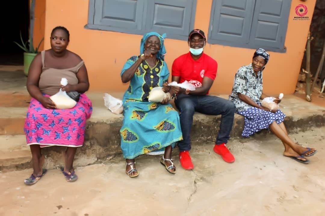 A group of people are sitting on the sidewalk in front of a building.