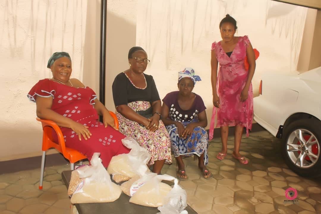 A group of women are sitting in front of a car.