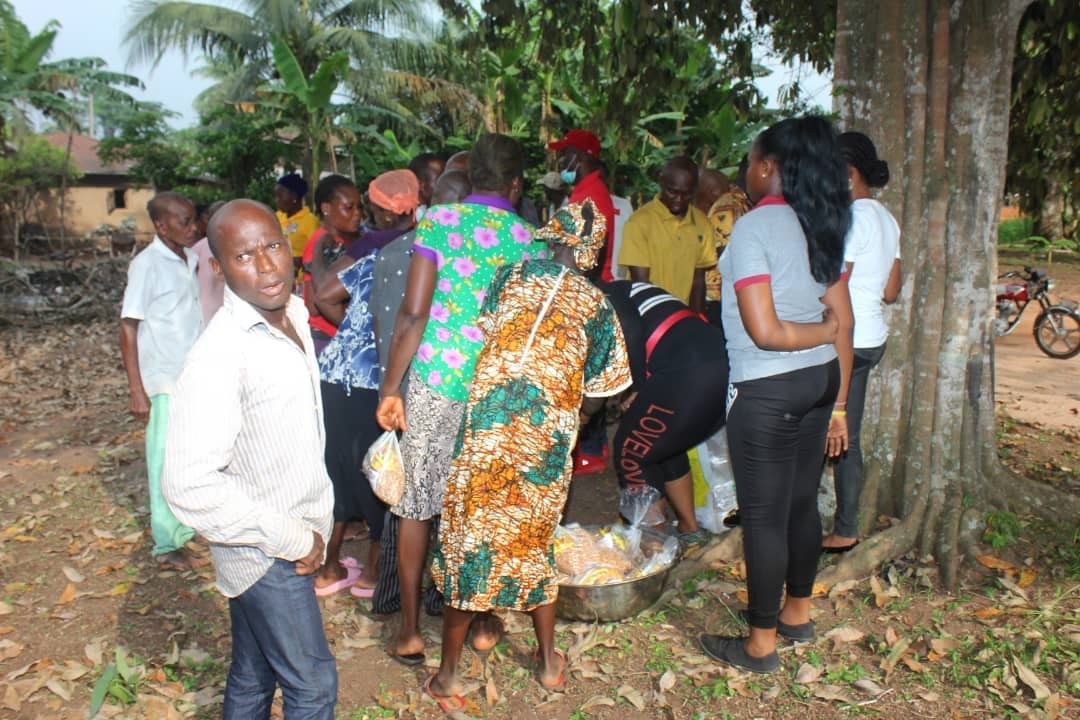 A group of people are standing around a tree in a field.