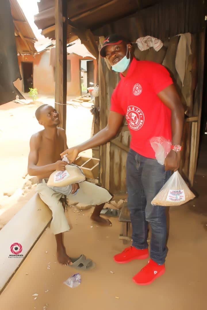 A man wearing a mask is giving a bag of food to another man.