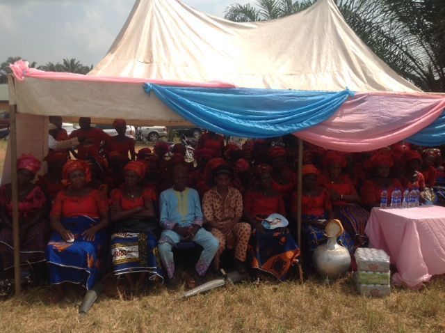 A group of people sitting under a tent in a field