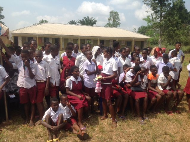A group of children are posing for a picture in front of a school.