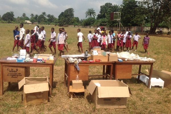 A group of children are standing in a field with tables and boxes
