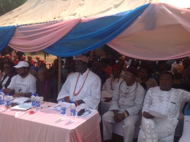 A group of men are sitting at a table under a tent.
