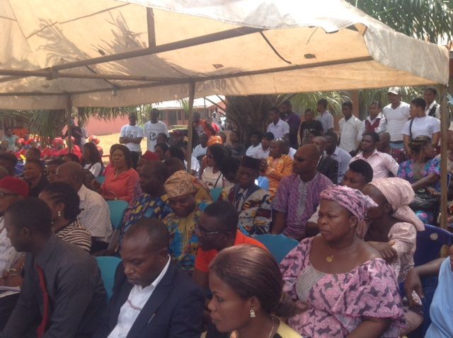 A large group of people are sitting under a tent.