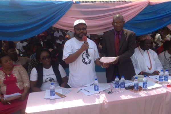 A man in a white shirt is speaking into a microphone