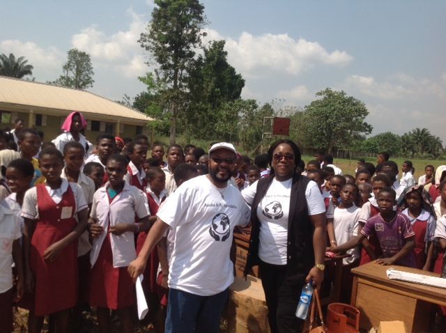 A man and a woman are standing in front of a crowd of children