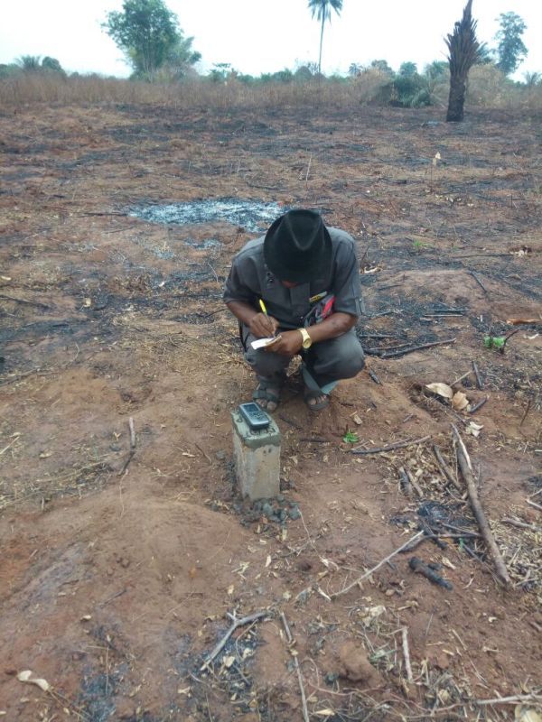 A man is kneeling down in a field writing on a piece of paper.