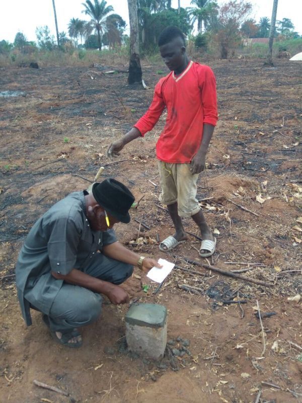 A man in a red shirt is kneeling next to another man