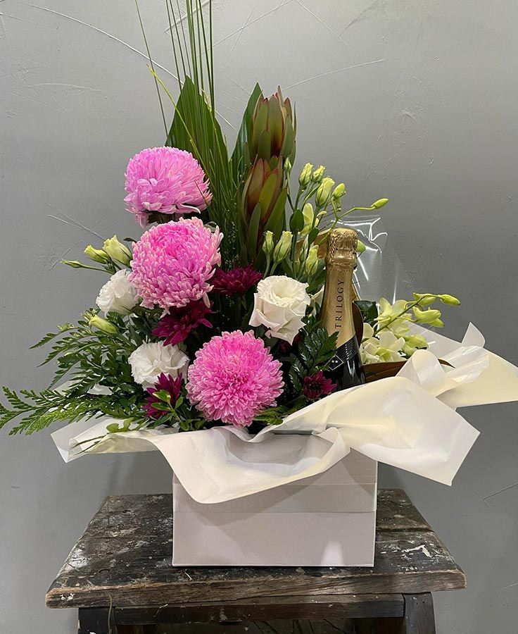 A White Box Filled With Pink and White Flowers and a Bottle of Champagne — Castletown Flower Hut in Pimlico, QLD