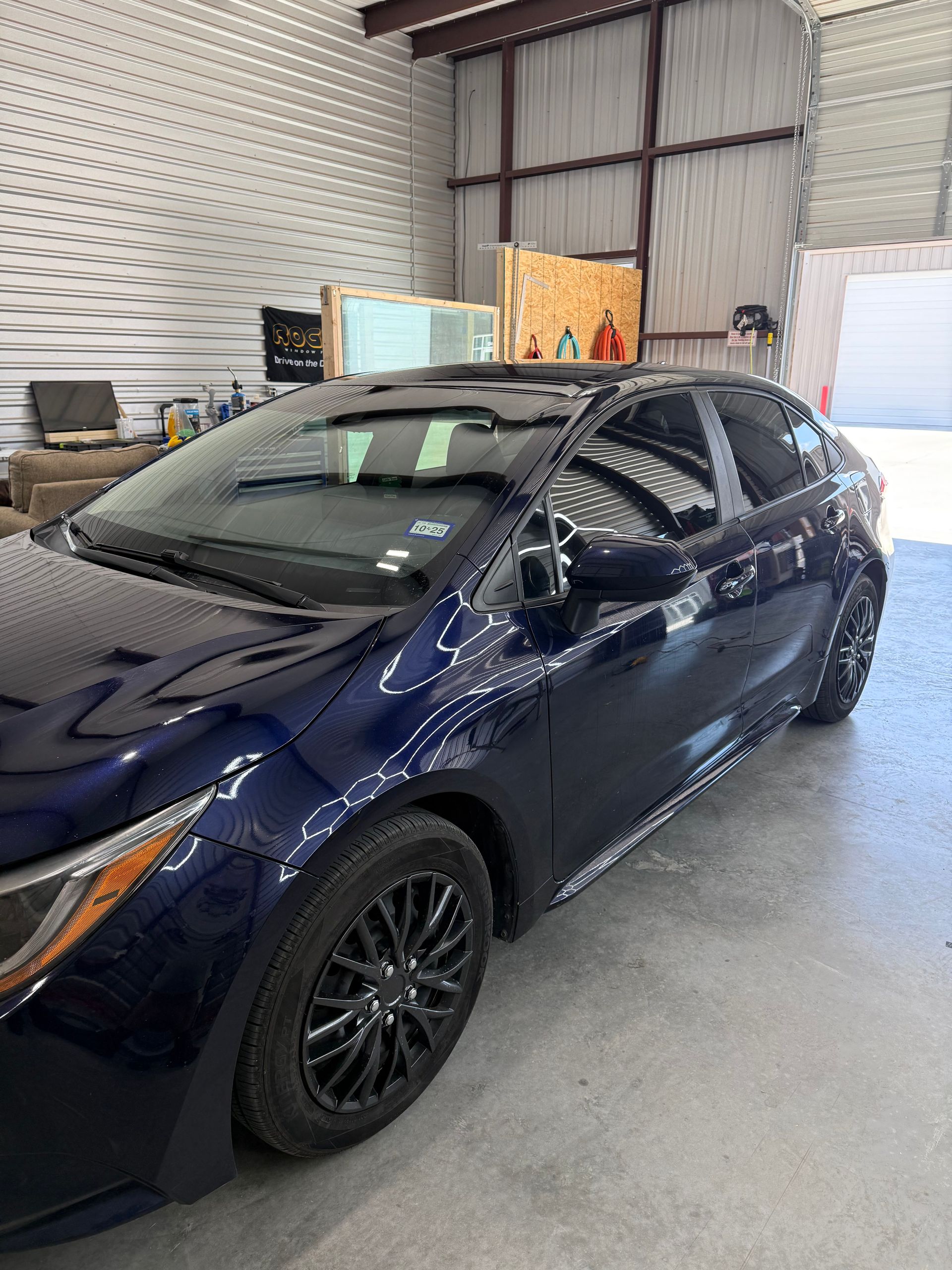 Dark blue Toyota Corolla hatchback in a garage.