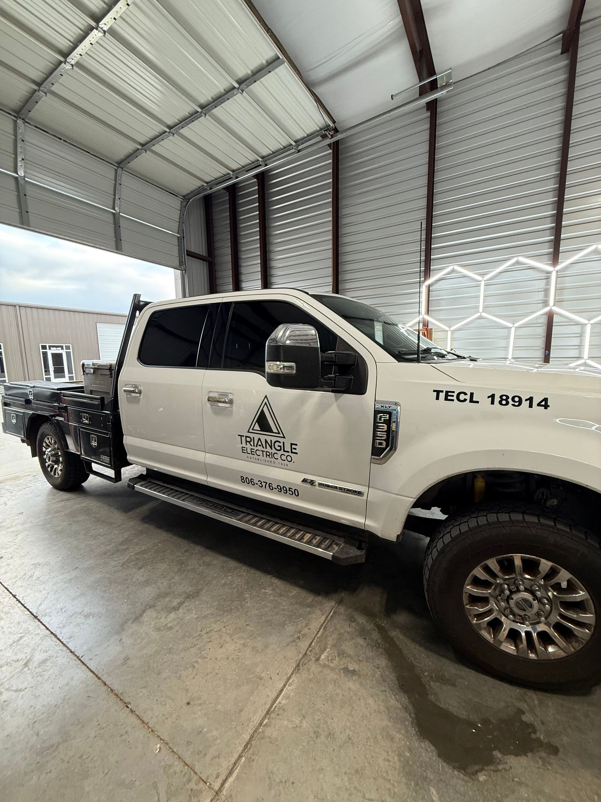 White flatbed truck inside a metal building with the words 