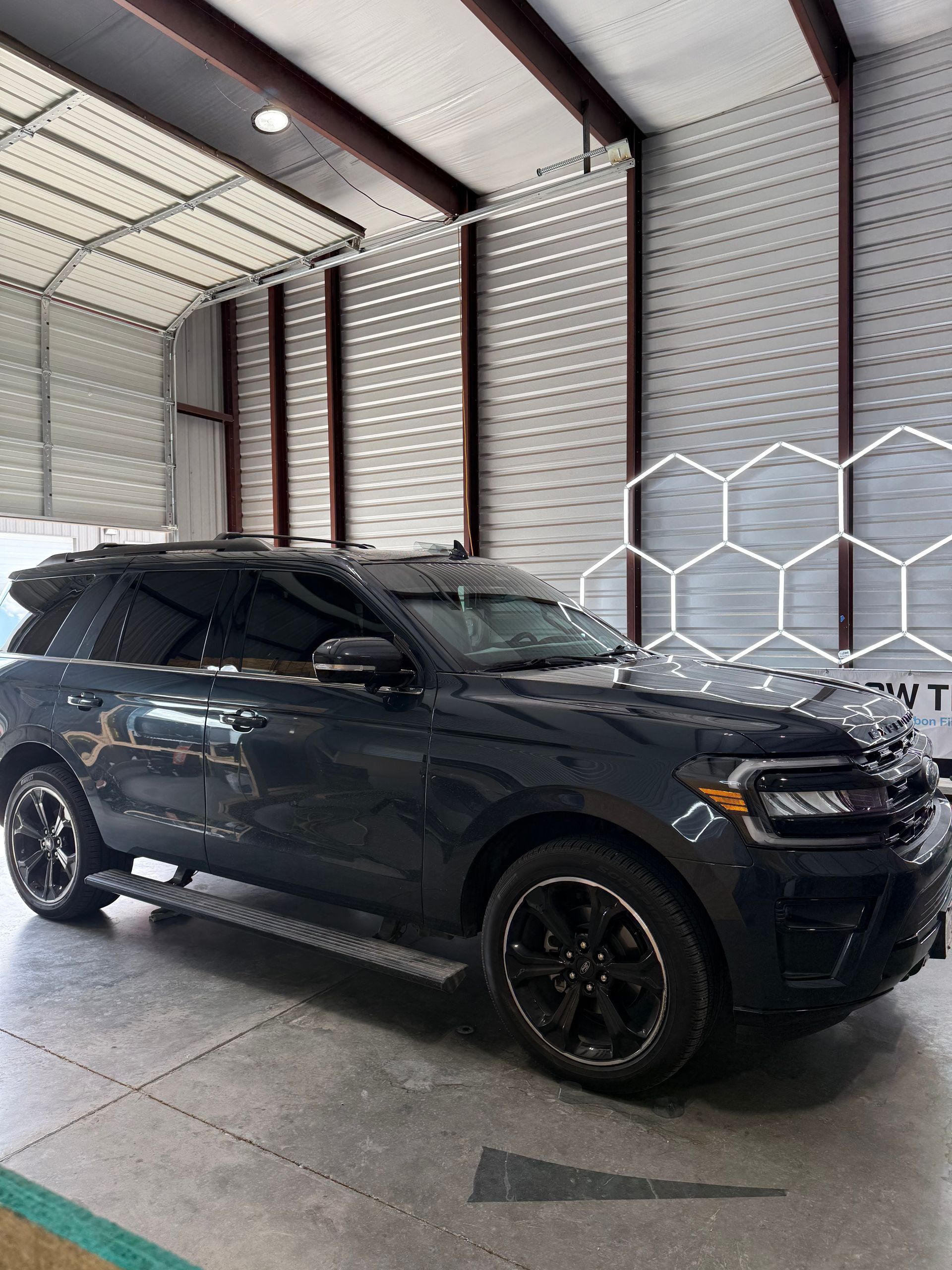 Dark SUV parked inside a garage, next to a geometric design on the wall.