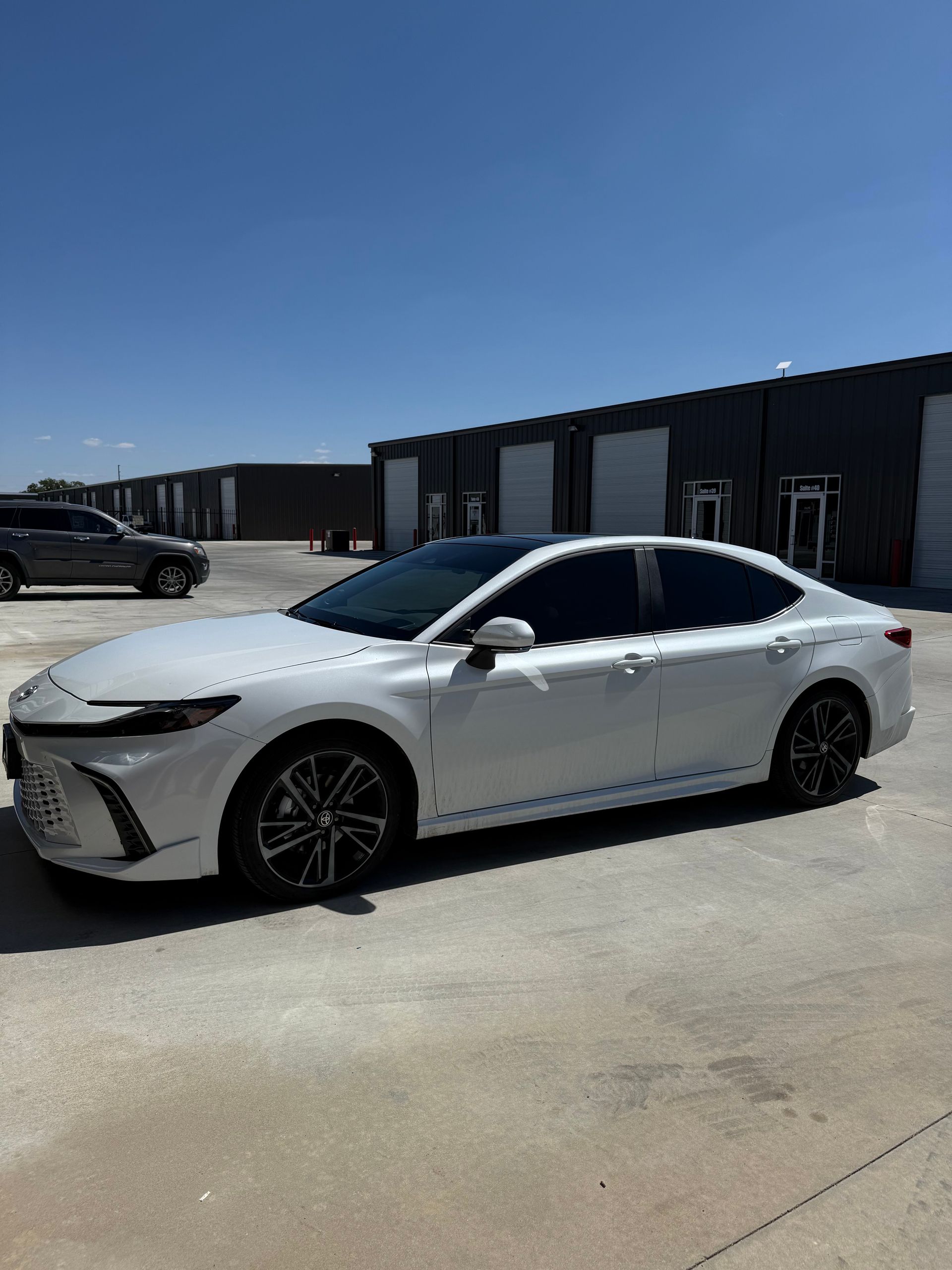 White Toyota sedan parked in front of buildings on a sunny day.