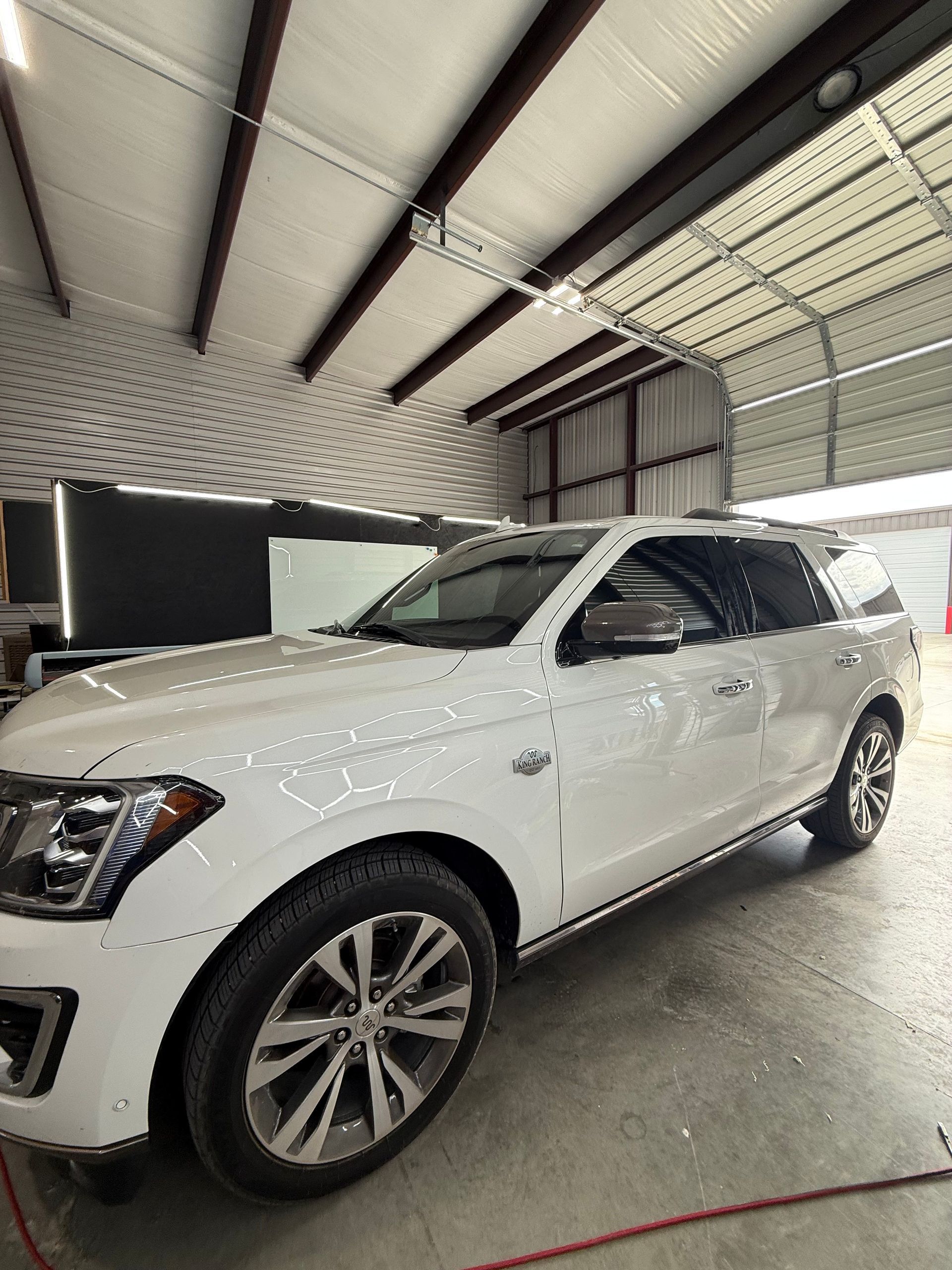 White SUV parked inside a garage, under bright lights.