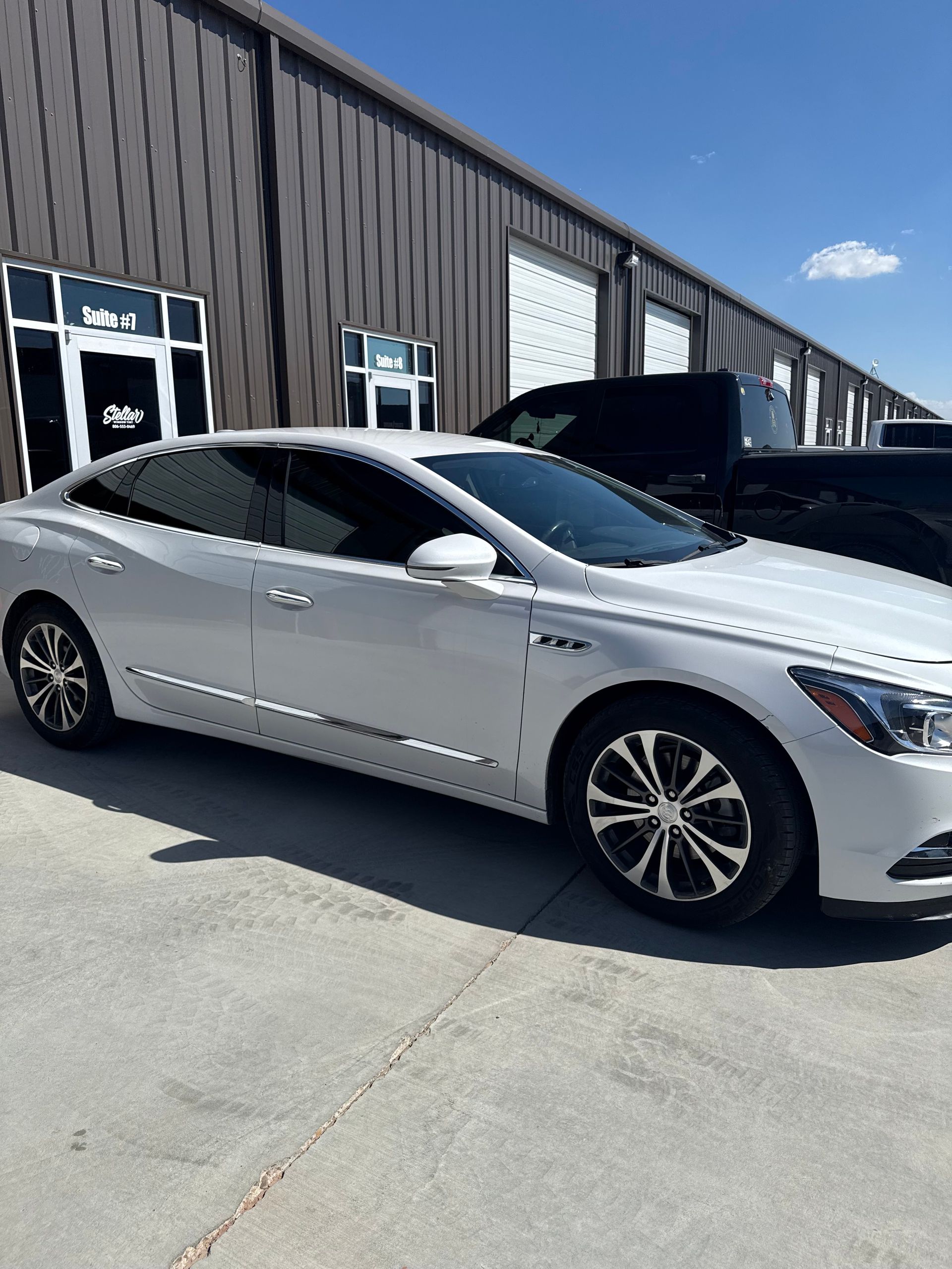 White Buick LaCrosse sedan with tinted windows parked in front of a building on a sunny day.