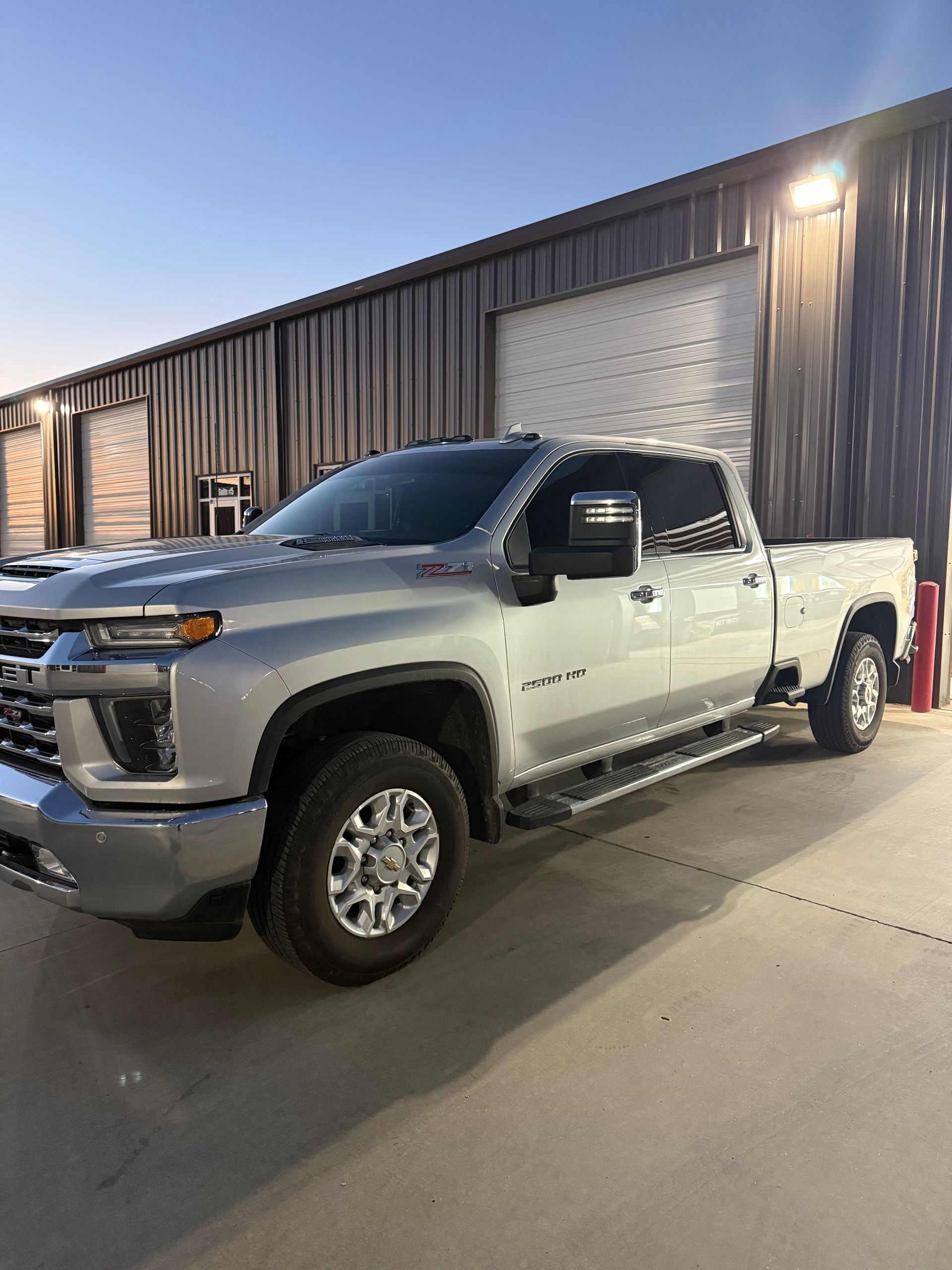 Silver Chevrolet pickup truck parked in front of a building with overhead lighting.
