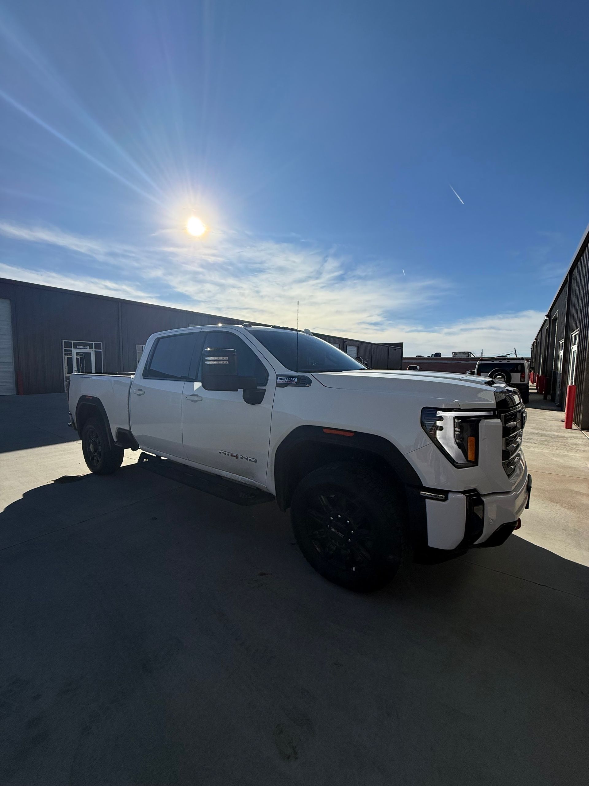 White GMC Sierra truck parked outdoors under a sunny blue sky.