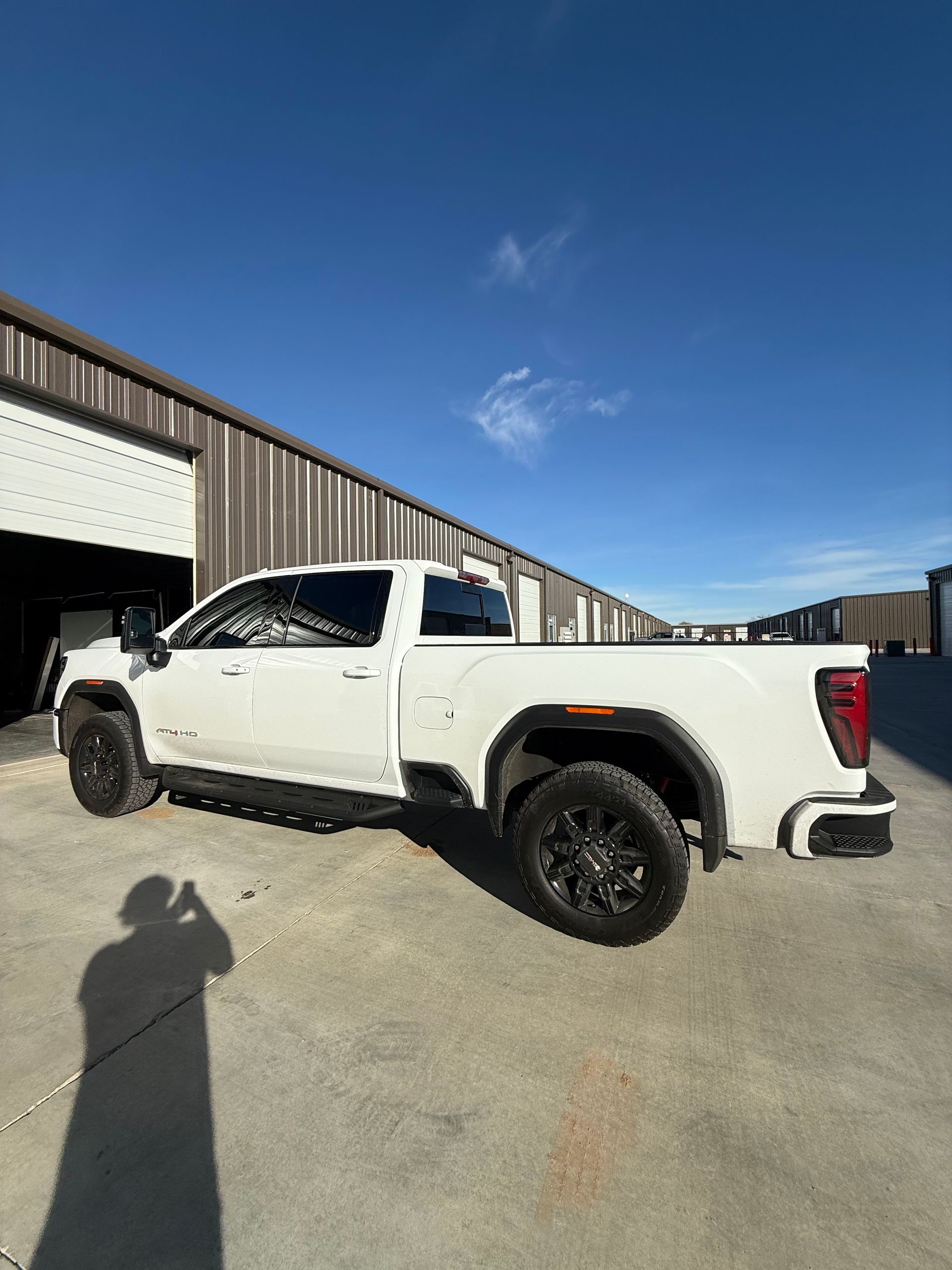 White GMC truck parked on concrete, near a building on a sunny day.