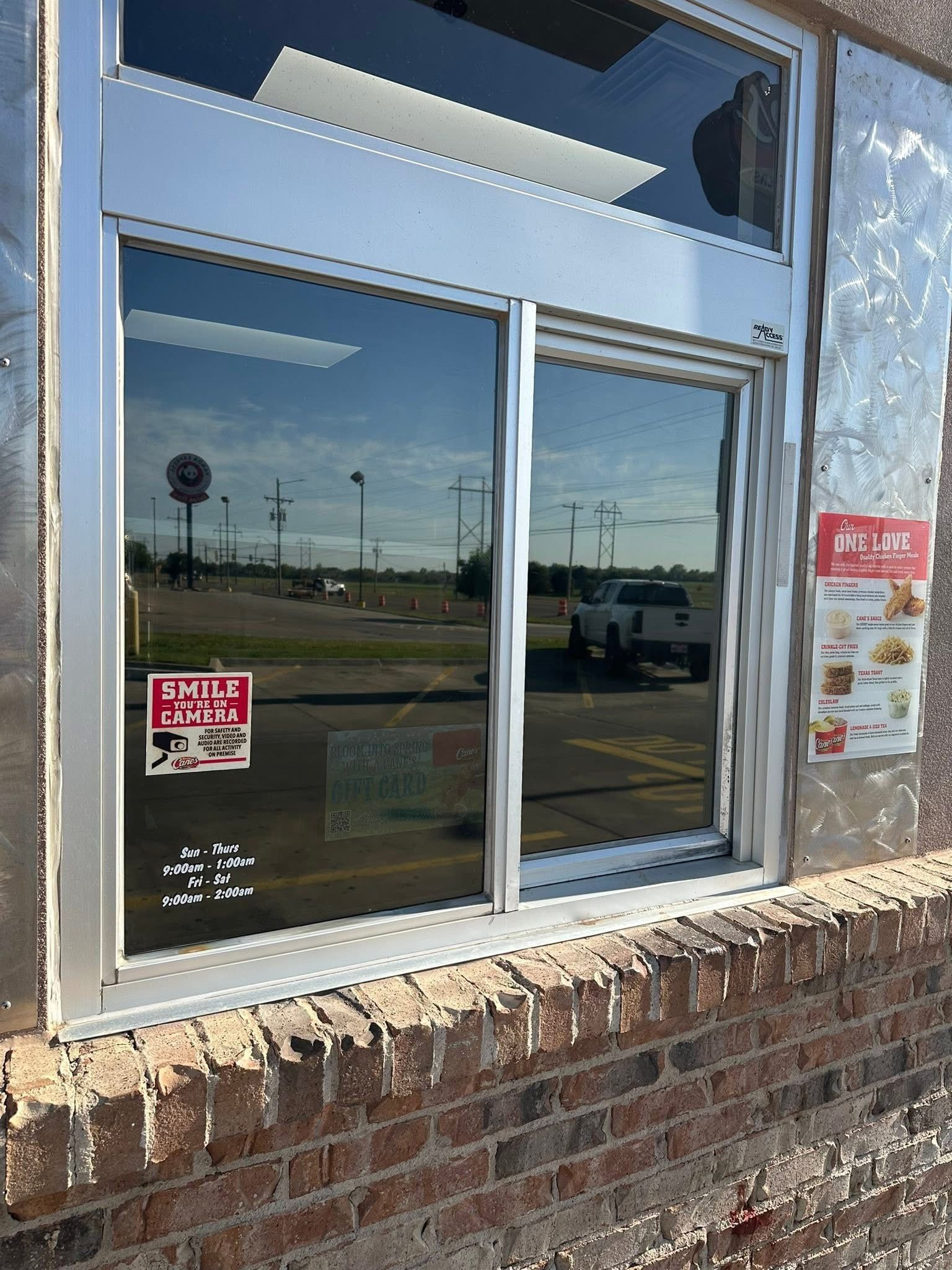 Drive-thru window with reflective glass, menu sign, brick wall.