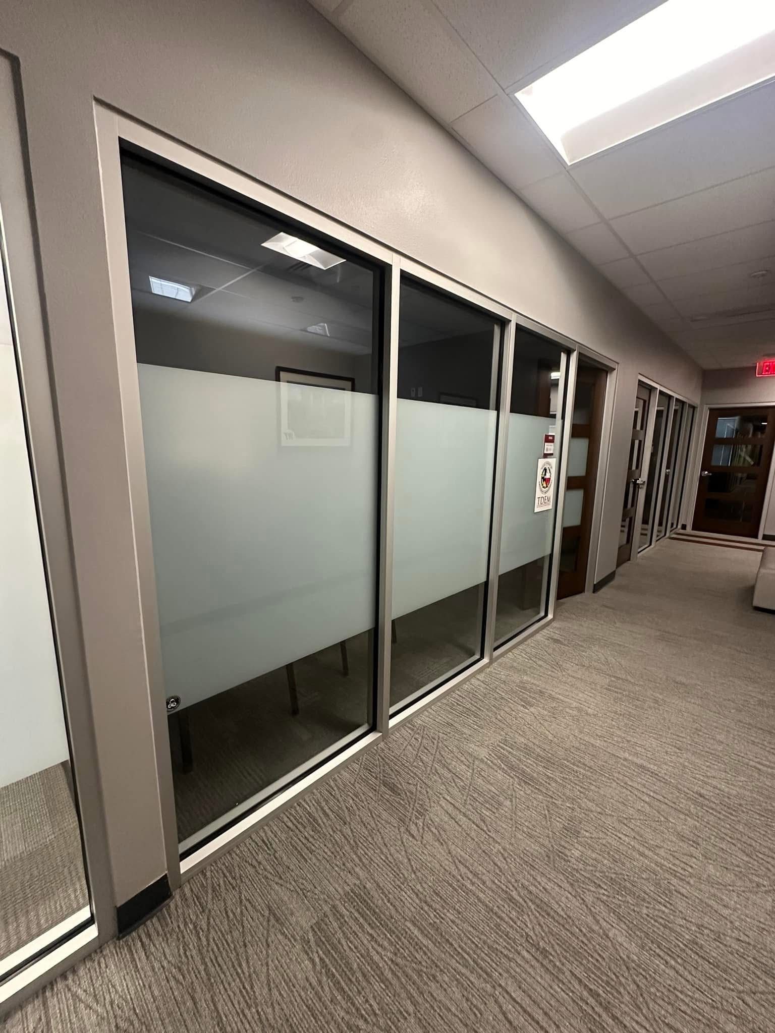 Hallway with frosted glass office doors, gray walls, and carpet.