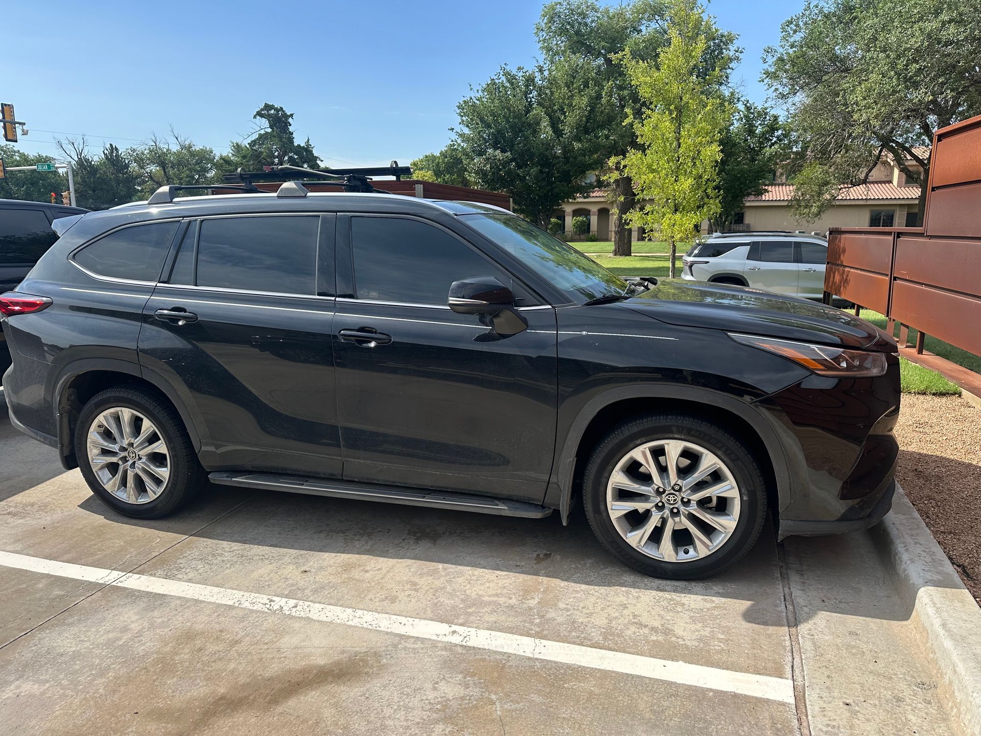 Black Toyota Highlander SUV parked in a parking spot on a sunny day.