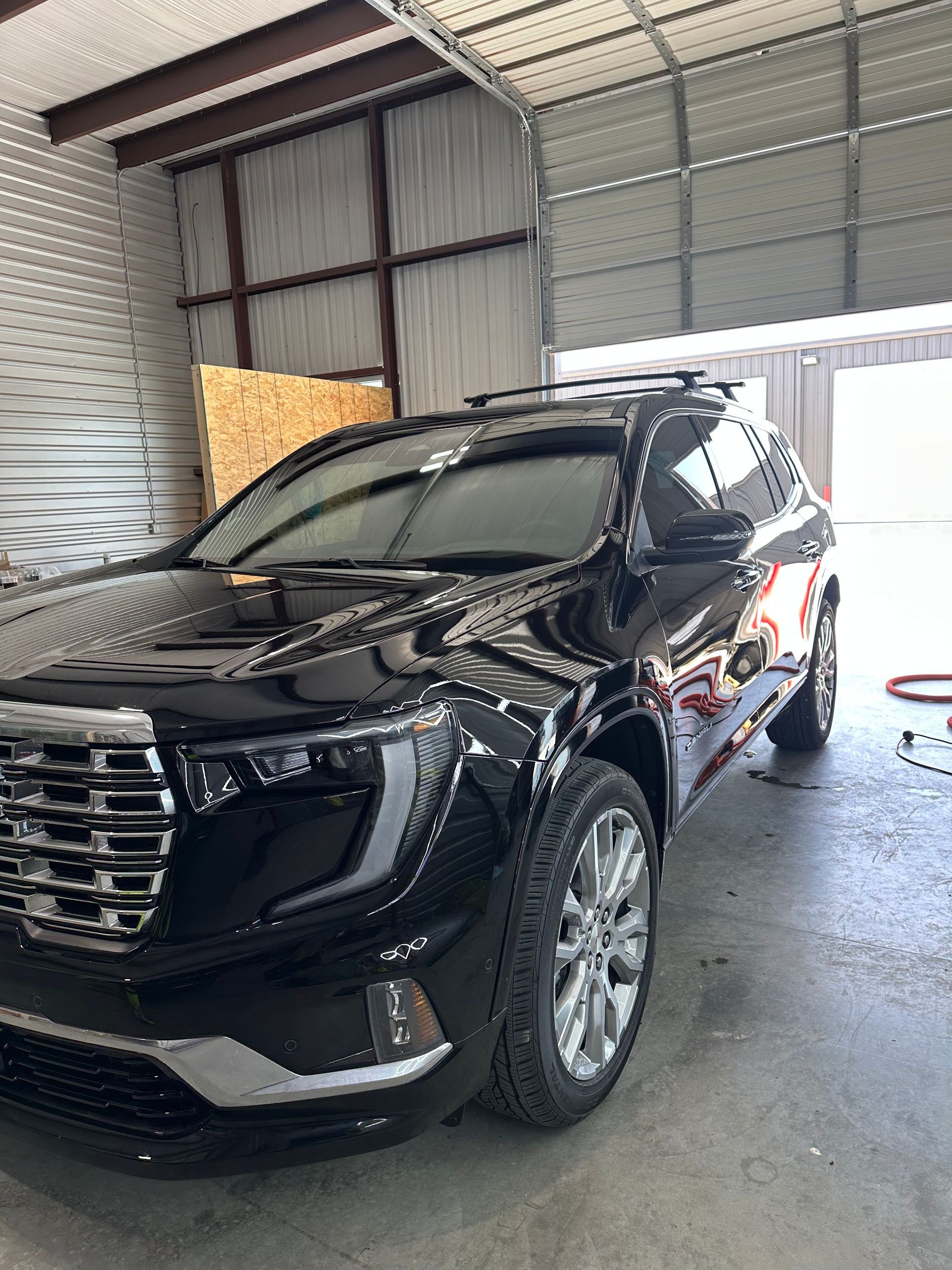 Black SUV parked inside a garage, under overhead lights.