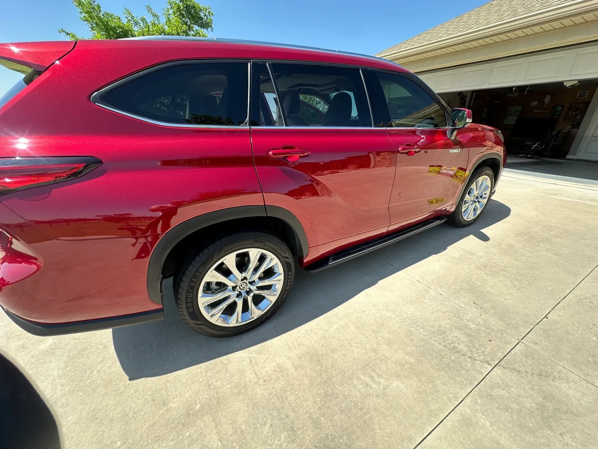Red SUV parked on a concrete driveway in front of a house on a sunny day.