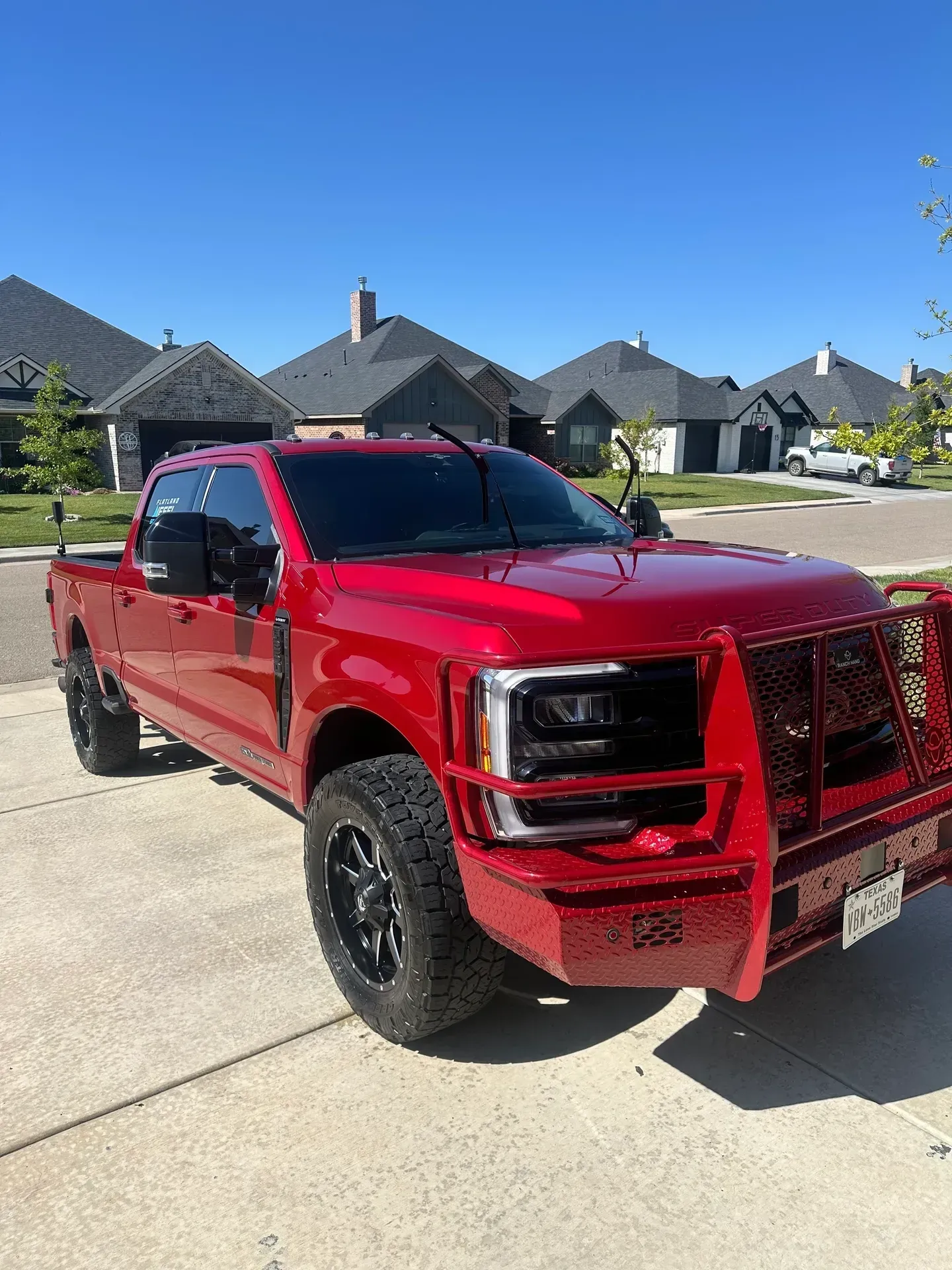 Red pickup truck parked on a driveway with a neighborhood background.