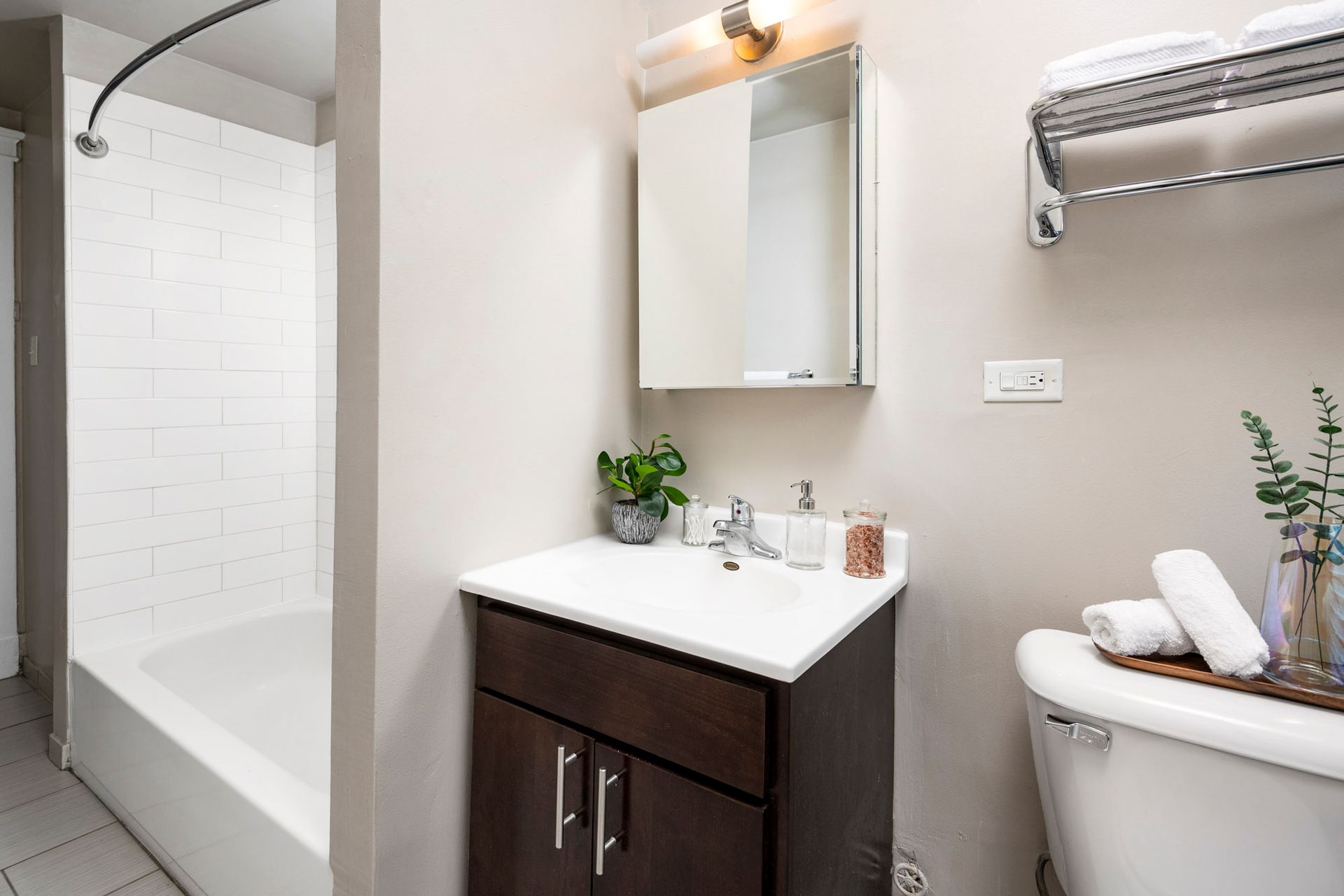 A bathroom with a sink, toilet, bathtub, and mirror at Reside on Irving Park.