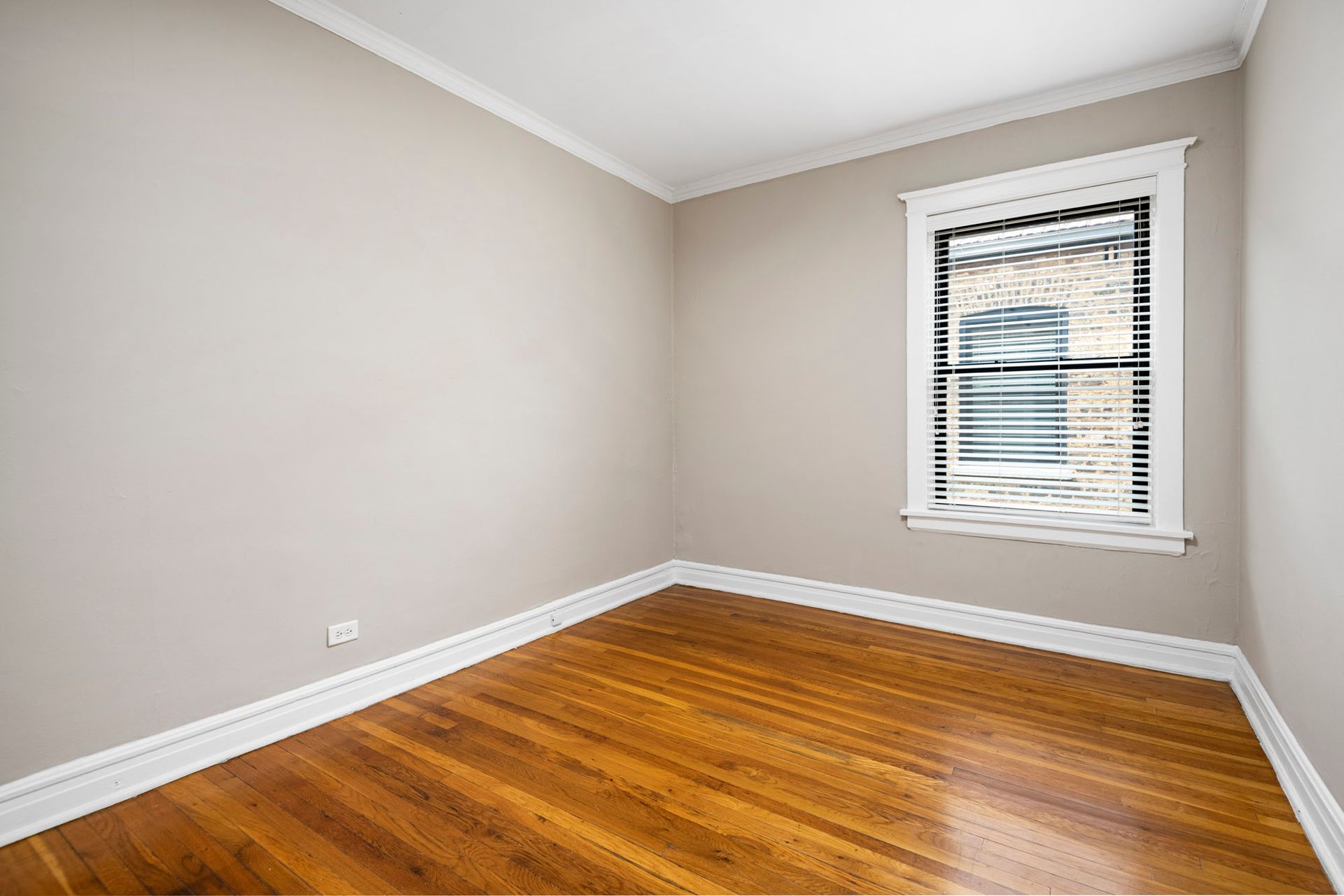 An empty room with hardwood floors and a window at Reside on Irving Park.