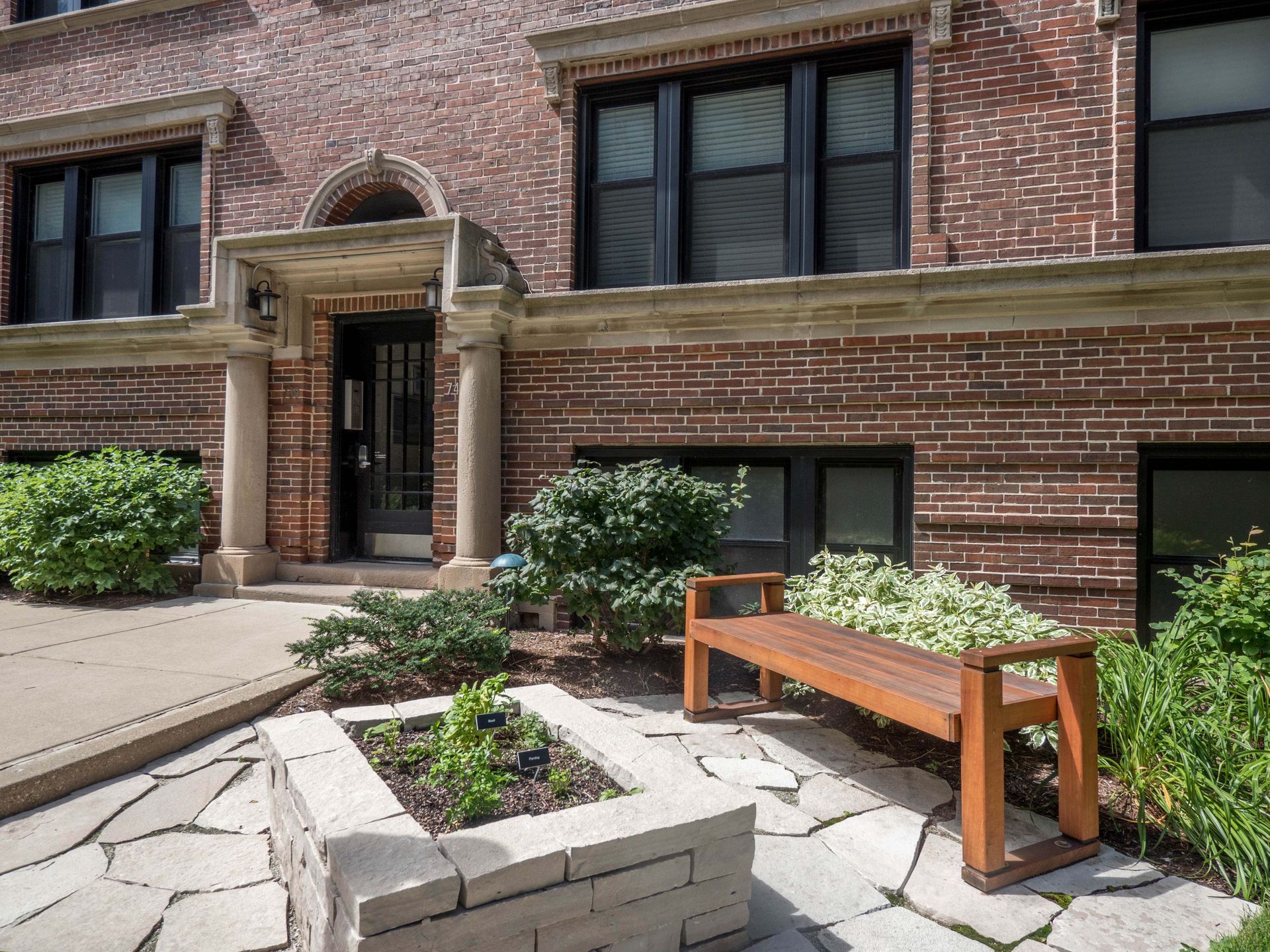 a courtyard with a bench and plants in front of a brick building