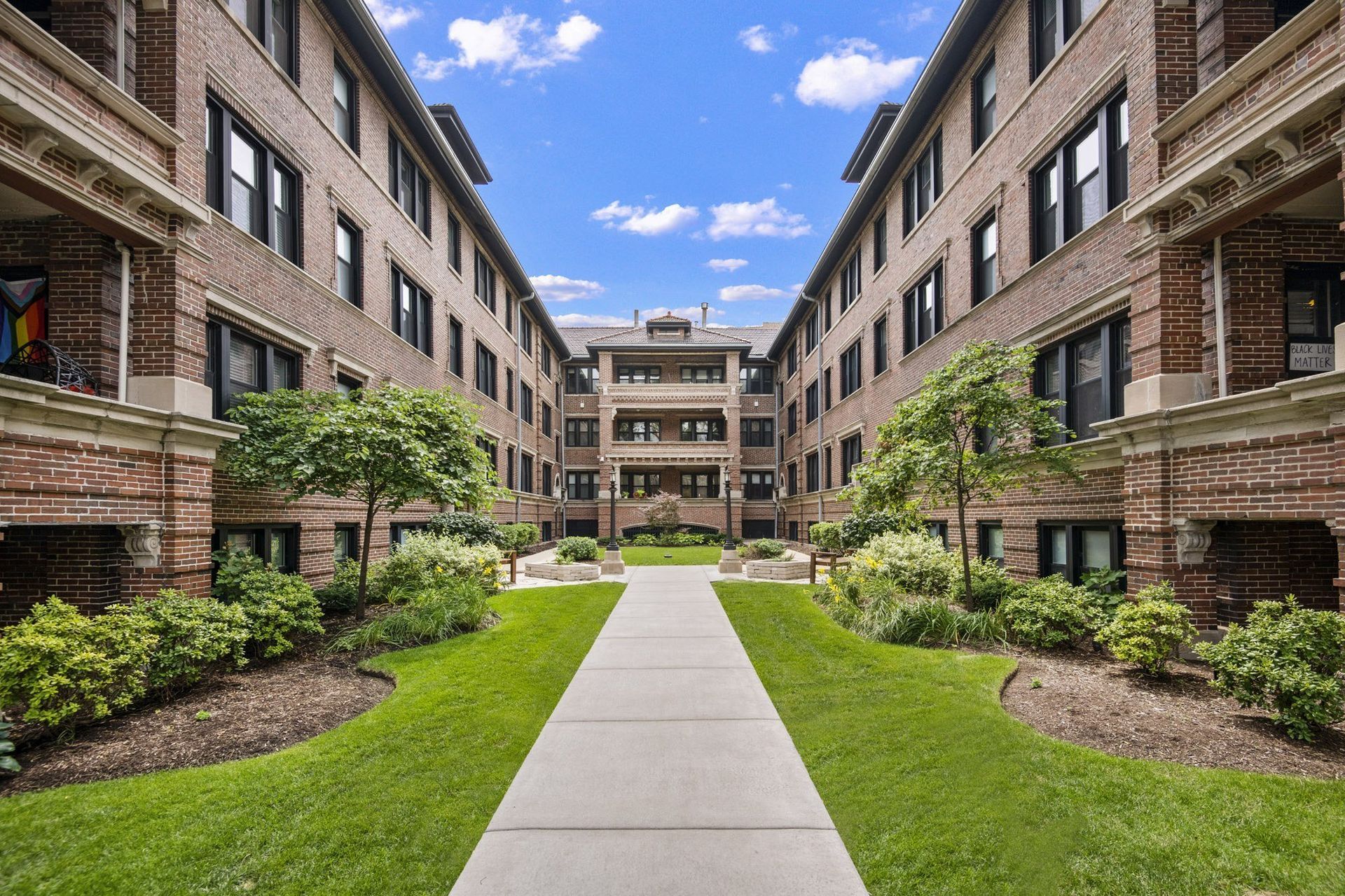 the courtyard between two large brick buildings with grass and trees