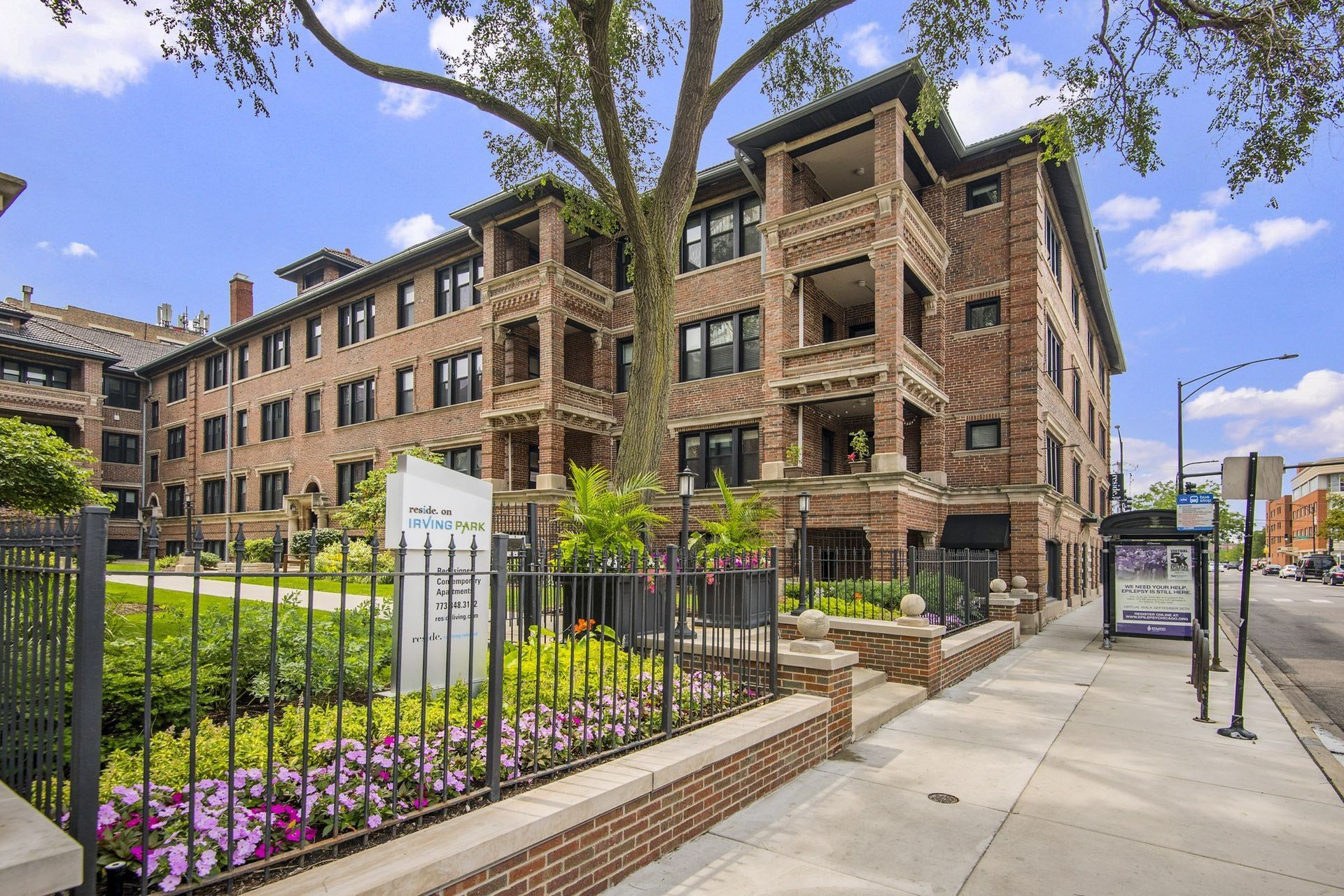 an apartment building with a sidewalk and a garden in front of it