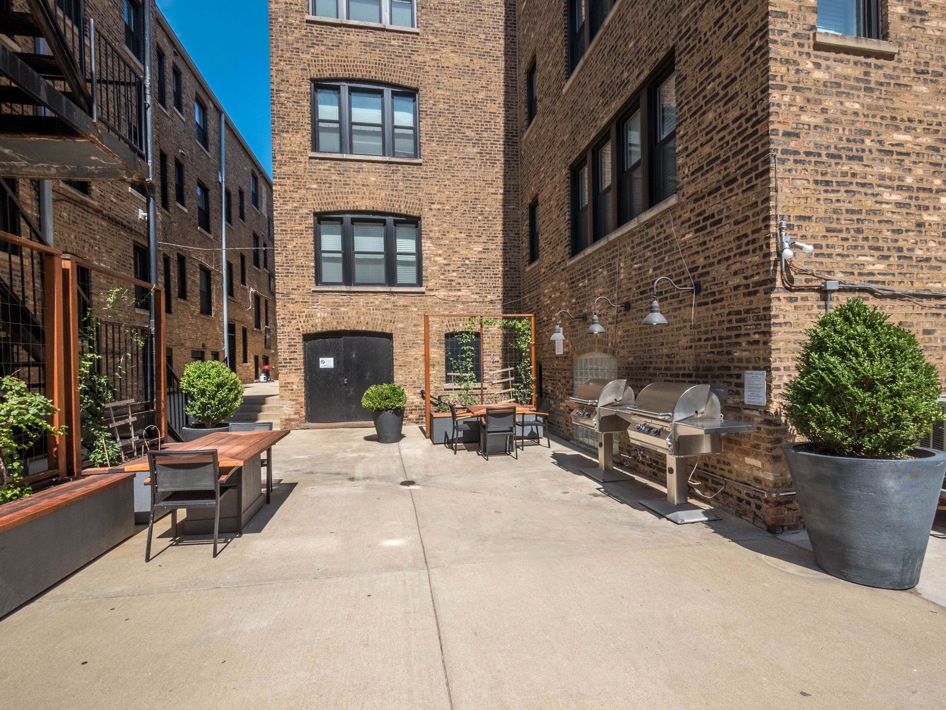 the yard of a brick building with a patio and a grill