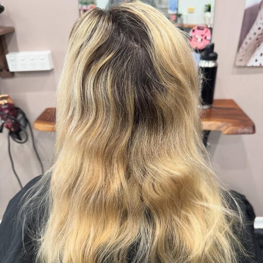 A Woman With Blonde Hair is Sitting in a Chair in Front of a Mirror — Ammo Hair and Beauty In Maclean, NSW
