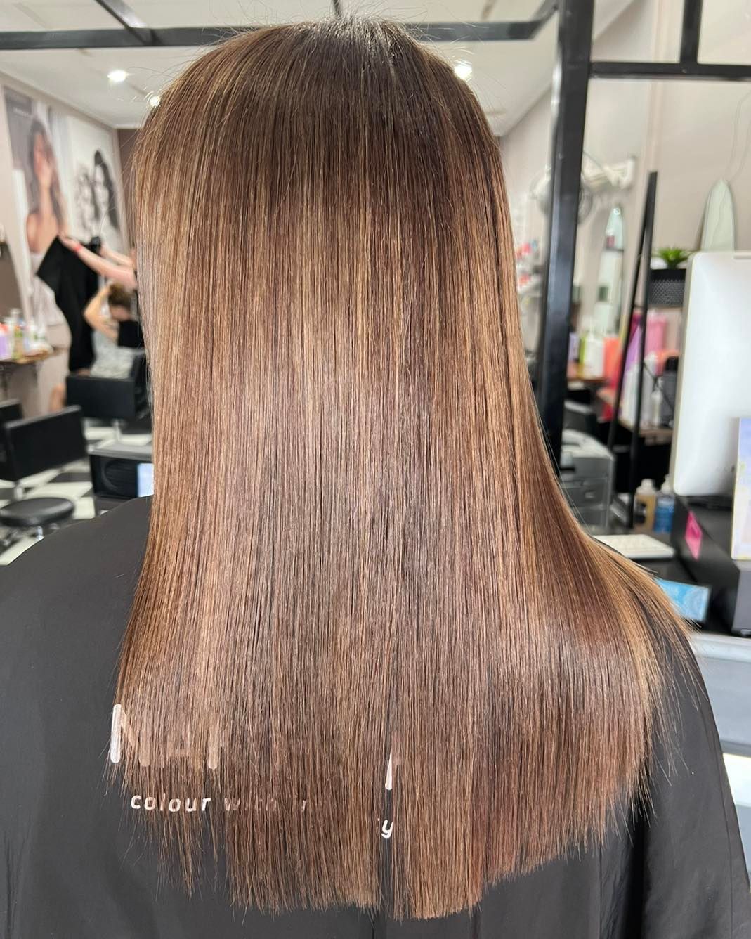 A Woman with Long Brown Hair Is Standing in A Salon — Ammo Hair and Beauty In Maclean, NSW