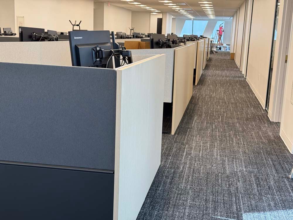 A long hallway in an office with cubicles and computers
